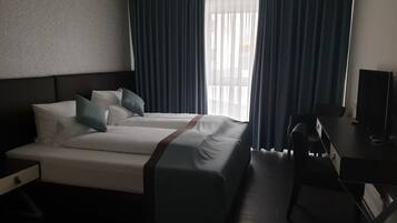 Ein Hotelzimmer mit Bett, Schreibtisch und Fernseher.