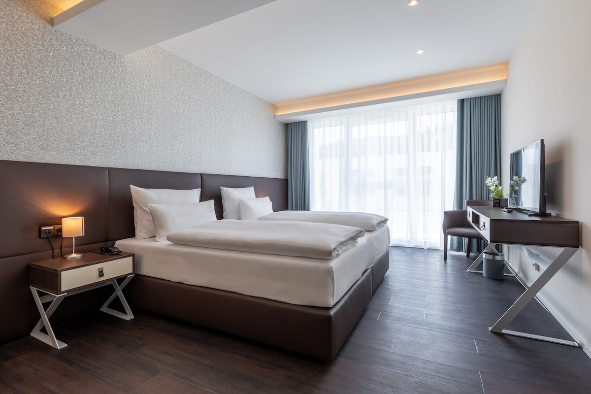 Una habitación de hotel moderna con una cama grande, un escritorio y una televisión.