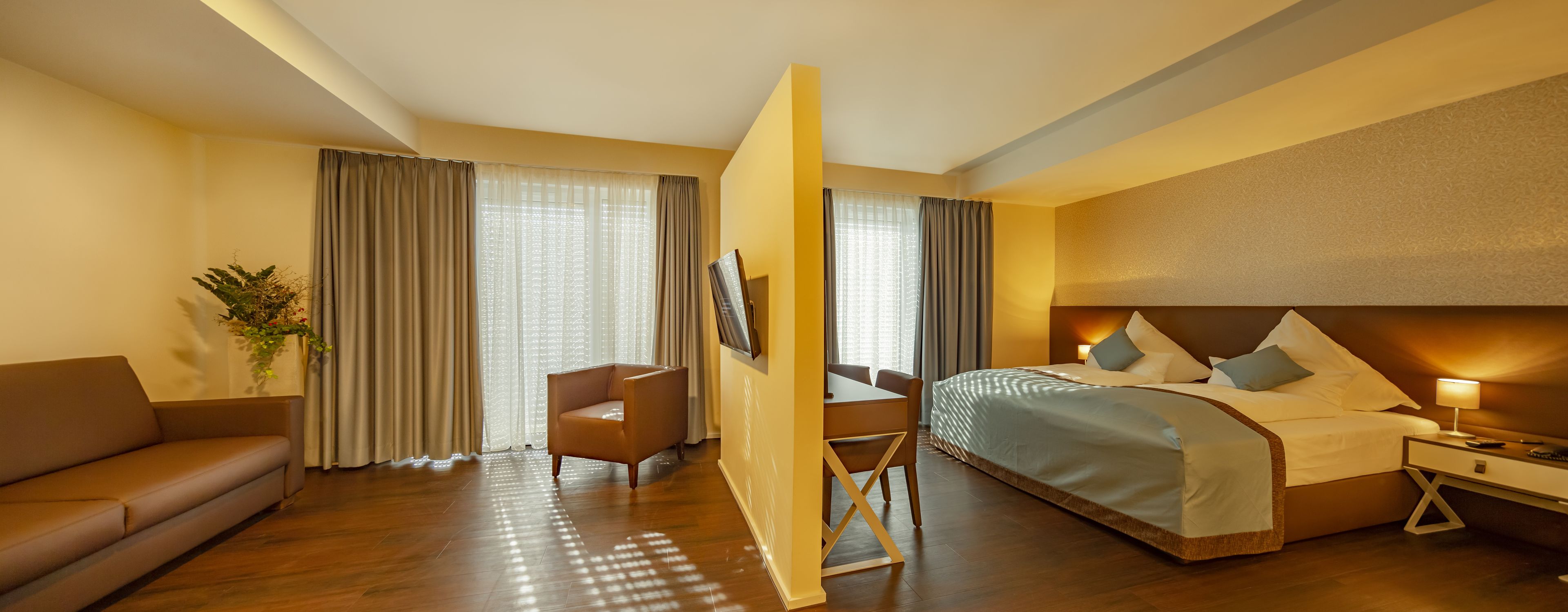 A hotel room with a bed, a sofa, a chair, a desk, and a nightstand.