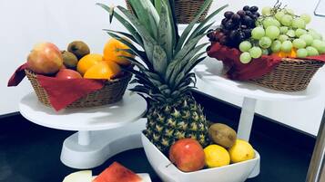 A fruit display with various fruits including bananas, grapes, apples, and oranges.