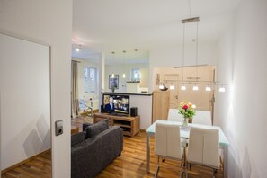 Una sala de estar moderna con televisor, sofá y comedor con sillas y mesa.