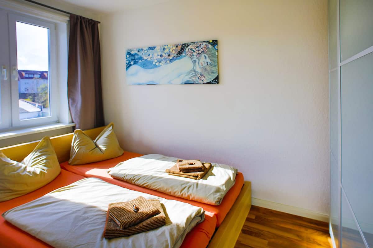 Une chambre avec deux lits, une fenêtre avec des rideaux et un tableau au mur.