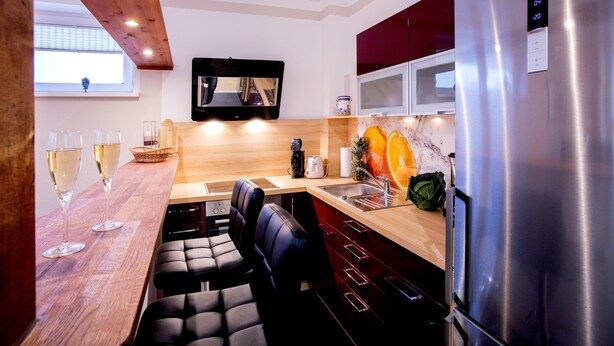 A modern kitchen with a wooden countertop, stainless steel appliances, and a built-in TV. - Ferienwohnungen Eicher Fritz Reuter Straße (Rostock)