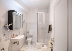Un baño moderno con lavabo, inodoro y ducha con mampara de vidrio.