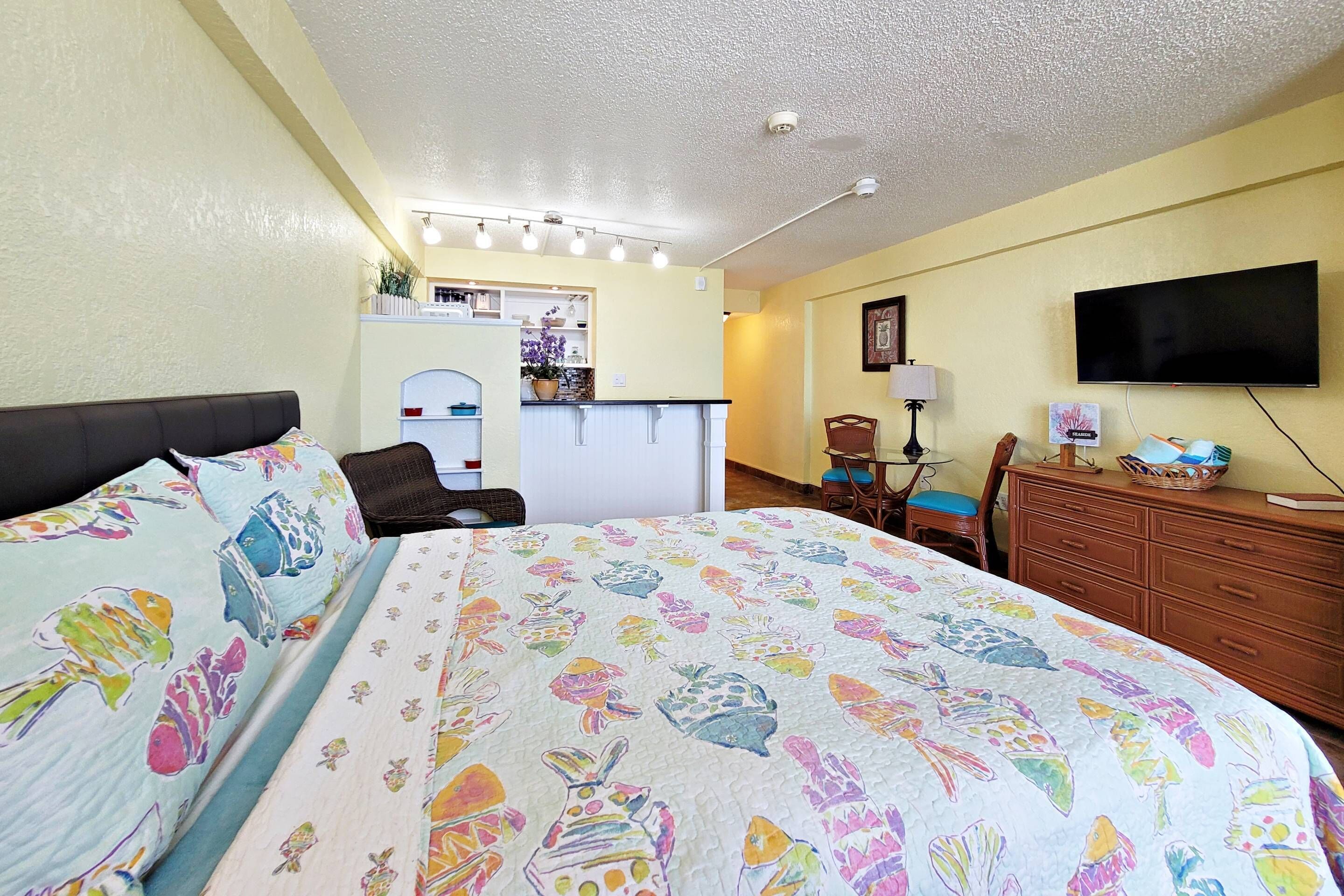 Une chambre d’hôtel comprenant un lit, un bureau, une chaise, une commode et un téléviseur.