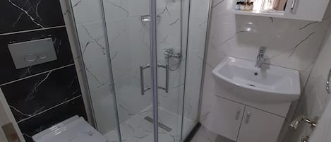 Un baño moderno con ducha acristalada, lavamanos blanco y retrete.