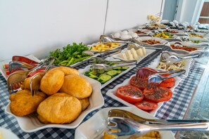 A buffet with various food items including bread, vegetables, and cheese. - Bozcaada Lara Hotel (Bozcaada)