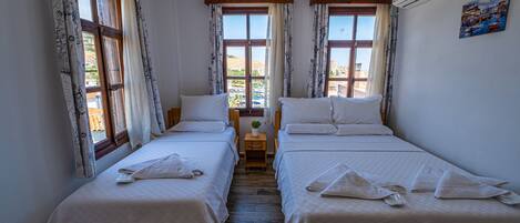 Una habitación con dos camas individuales, una mesita y una ventana con cortinas.