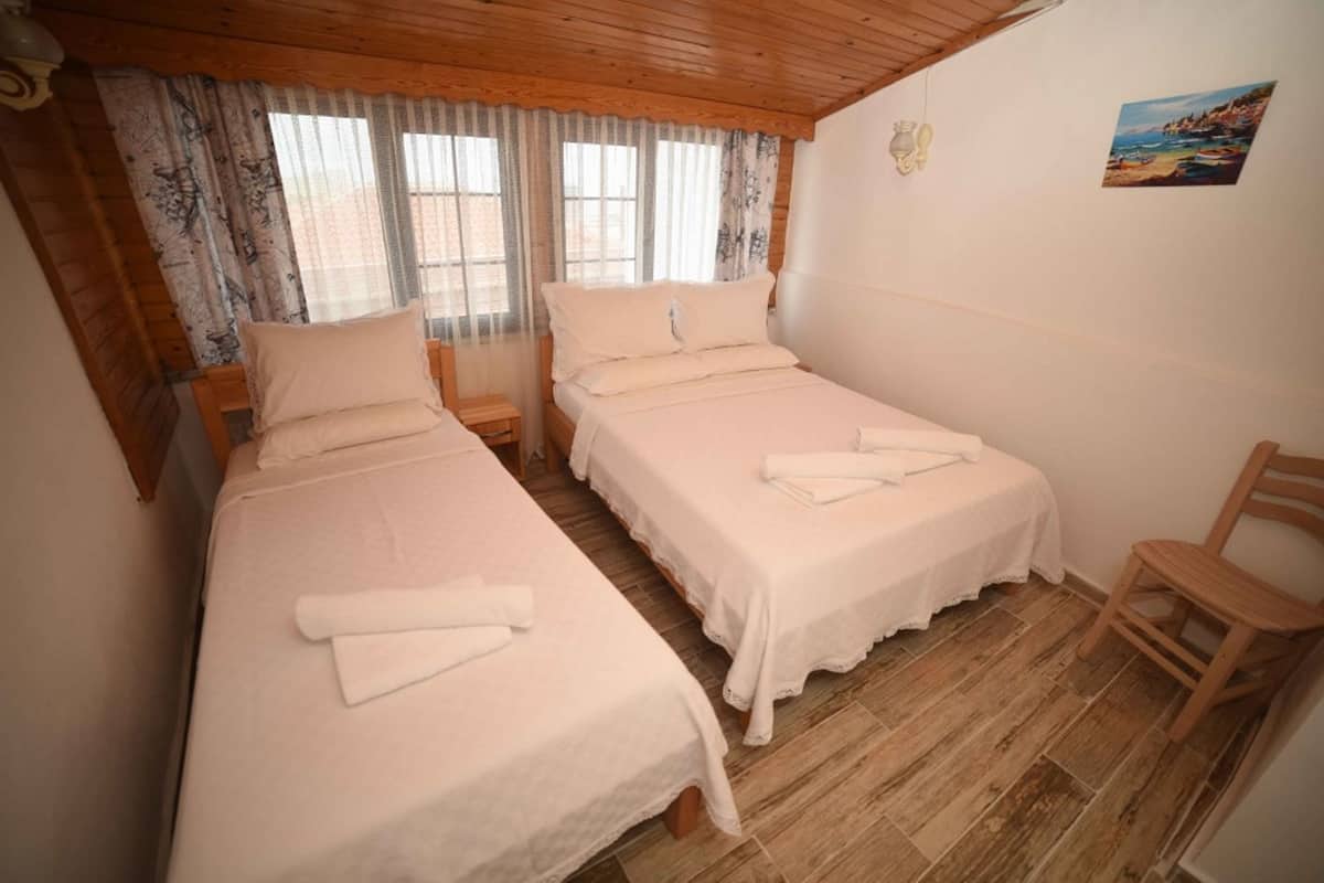 Una habitación con dos camas individuales, suelo de madera y una silla.