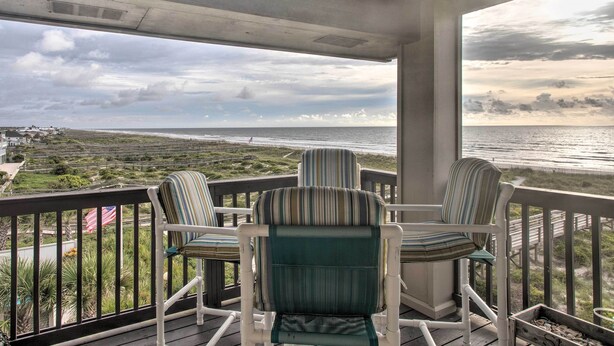 A balcony with three striped chairs and a view of the ocean. - Fernandina Beach Villa w/ Remarkable Ocean Views! (Fernandina Beach)