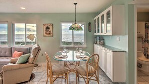 A dining area with a glass table, wicker chairs, and a view of the ocean through large windows. - Fernandina Beach Villa w/ Remarkable Ocean Views! (Fernandina Beach)