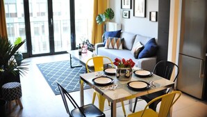 A modern living room with a sofa, dining table, chairs, and a kitchen area with a refrigerator. - 3D Szlak Apartament (Kraków)