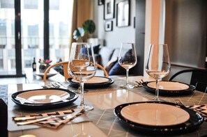 A dining table set with plates, cutlery, and wine glasses, with a modern interior and a view of the city. - 3D Szlak Apartament (Kraków)