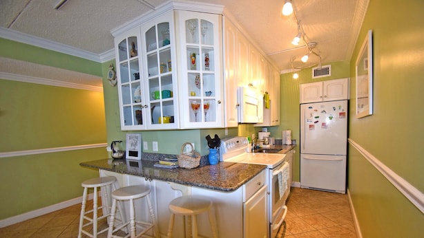 A kitchen with a central island, white cabinets, and a refrigerator. - Seatime 303S-Oceanside 136th St, Free WiFi, Pool, Elev, W/D, AC (Ocean City)