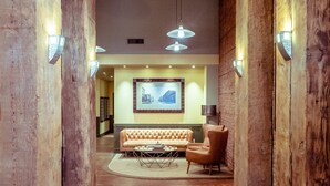 A lobby with wooden columns, a sofa, a chair, a coffee table, and pendant lighting. - Modern studio in the heart of the city (Seattle)