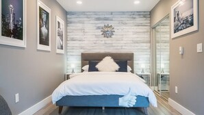 A modern bedroom with a large bed, a glass door leading to a bathroom, and framed cityscape pictures on the walls. - Modern studio in the heart of the city (Seattle)