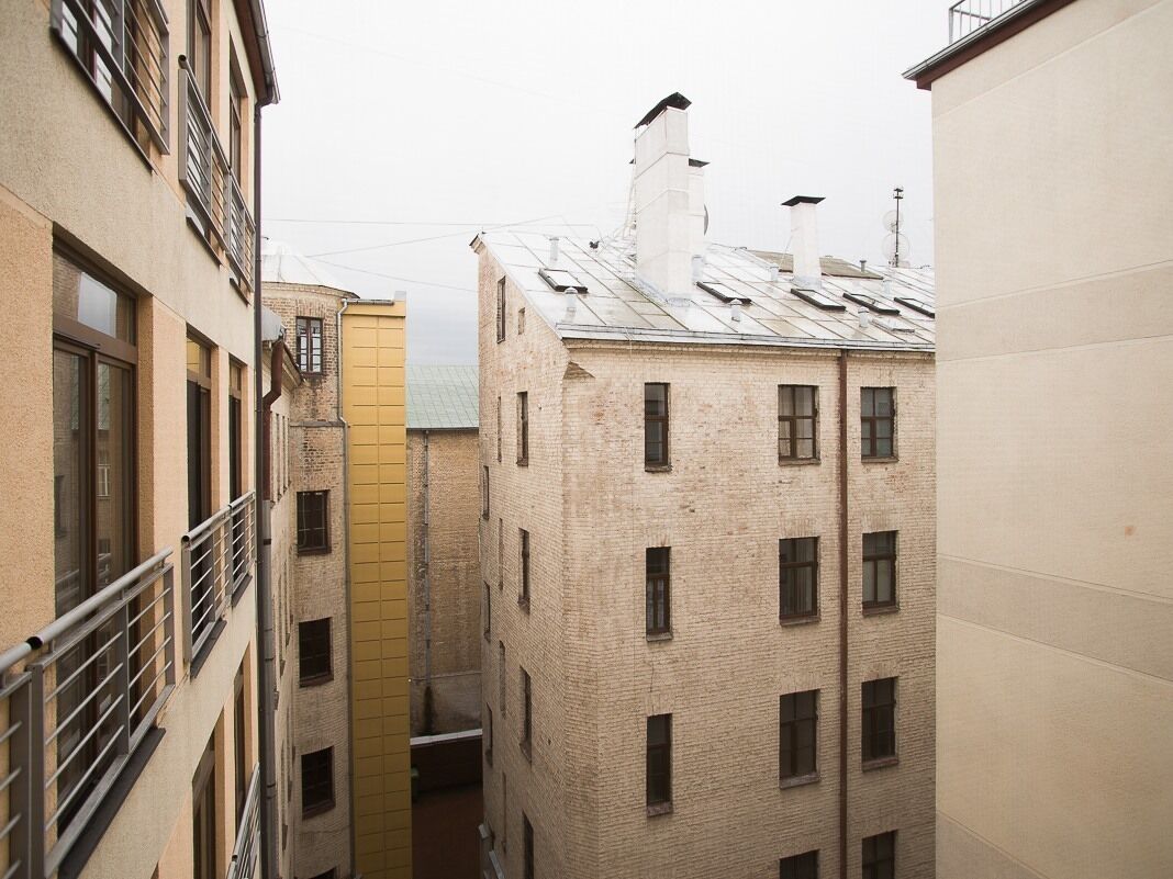 Une ruelle étroite, située entre des immeubles aux façades en briques et aux balcons en métal.