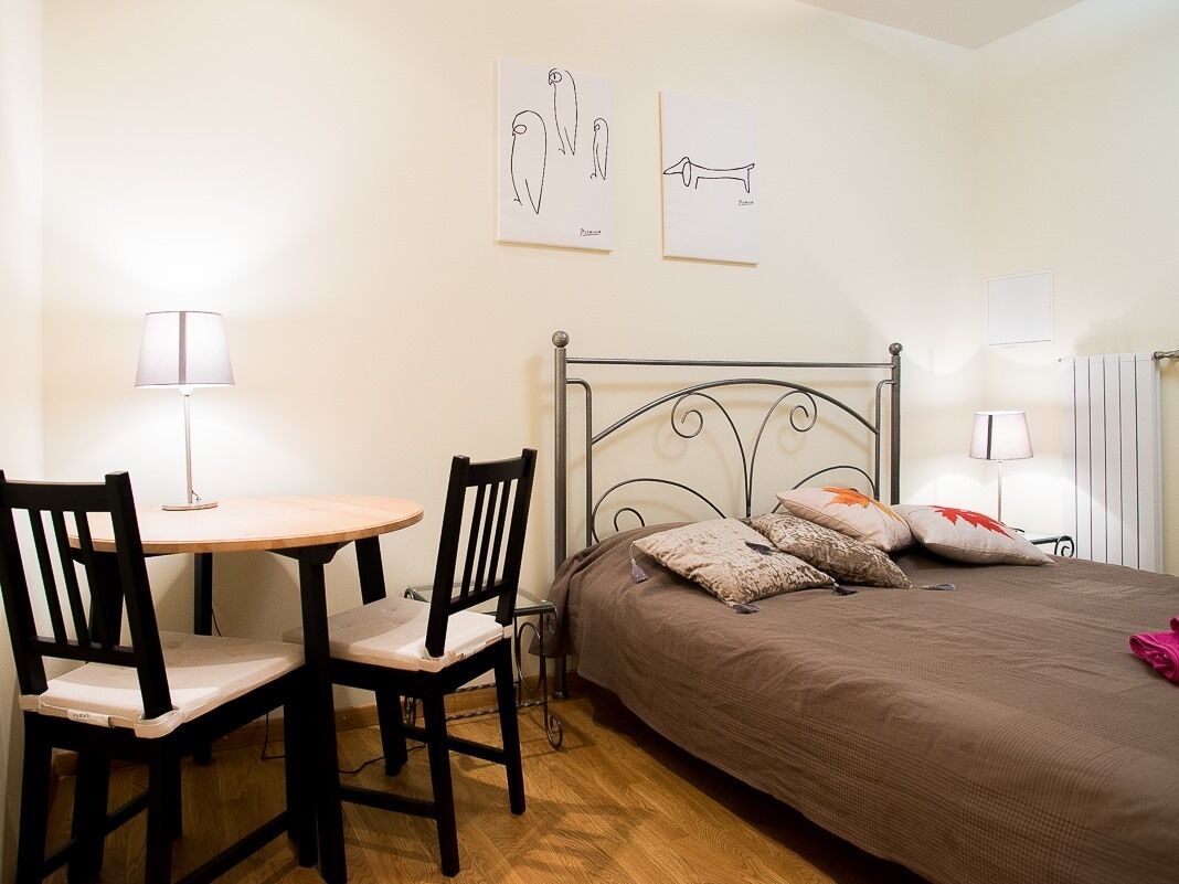 Una camera da letto con un letto, un comodino, due sedie e una lampada.