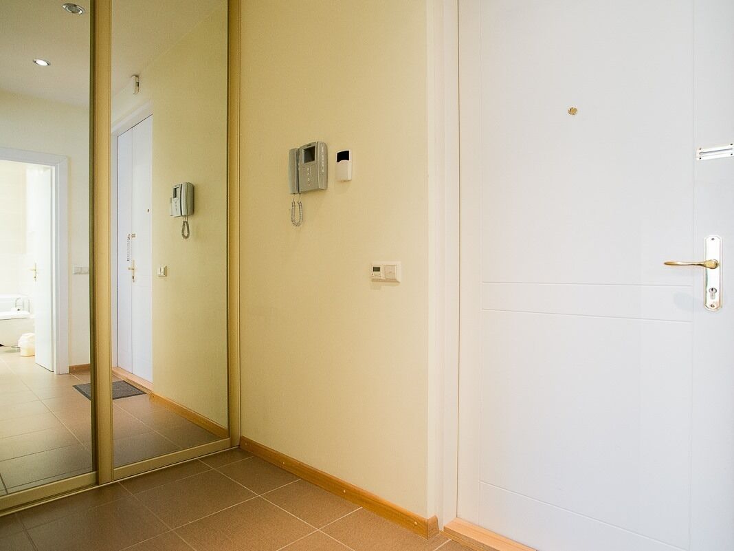 Ein Hotelzimmer mit weißer Tür, einem an der Wand montierten Telefon und einem kleinen Lichtschalter.