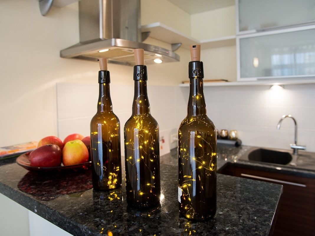 Three bottles with a light bulb inside on a kitchen counter.