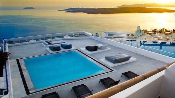 A rooftop pool area with lounge chairs and a swimming pool, overlooking a scenic coastal view. - Amity Suites - Adults Only (Santorini)