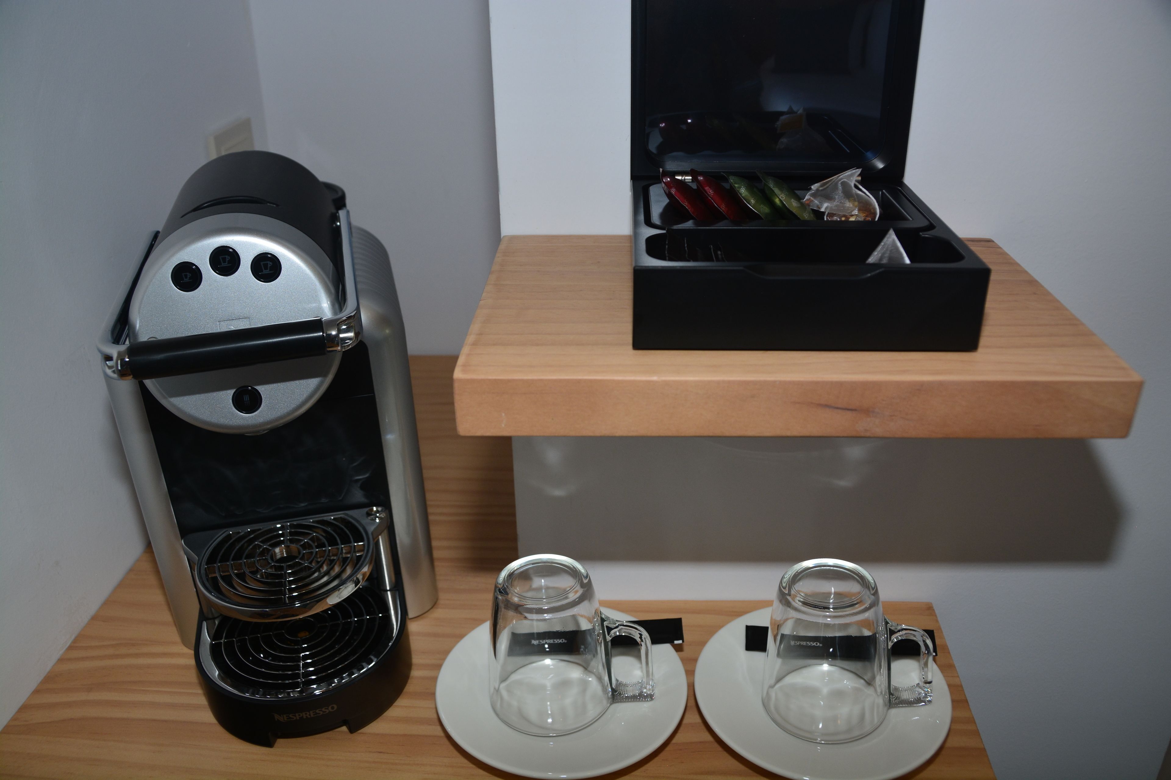 Una cafetera y dos tazas sobre una mesa de madera.