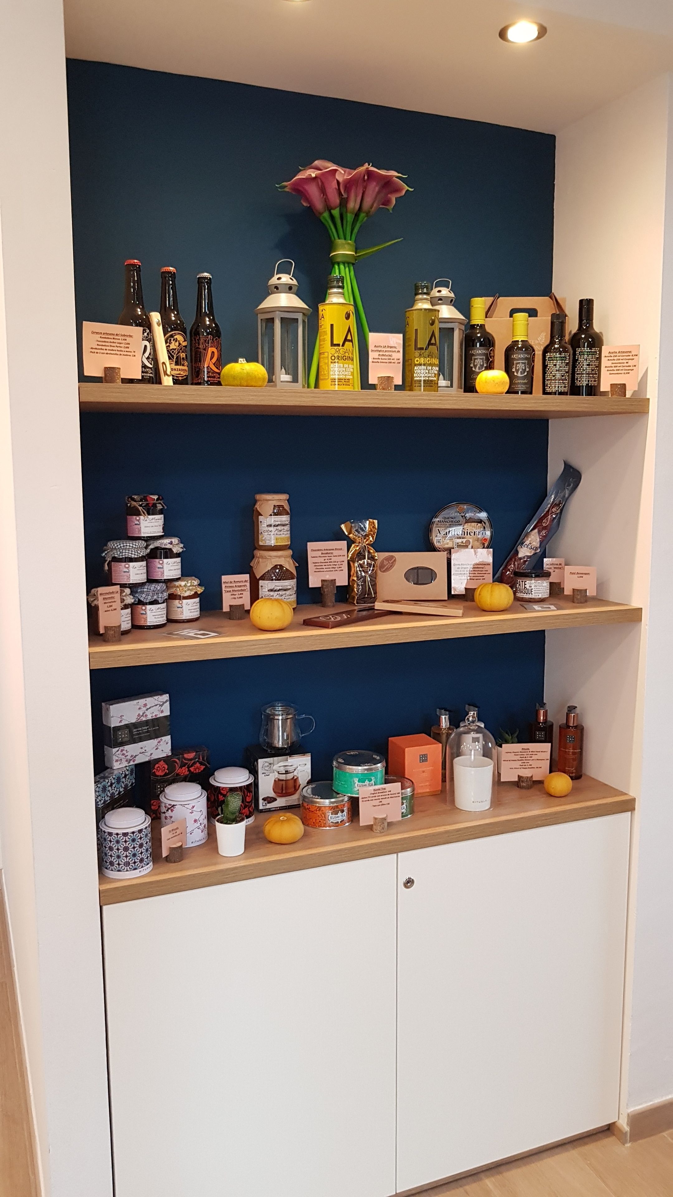 Una cocina con estantes de madera que muestran diversos alimentos y utensilios de cocina.