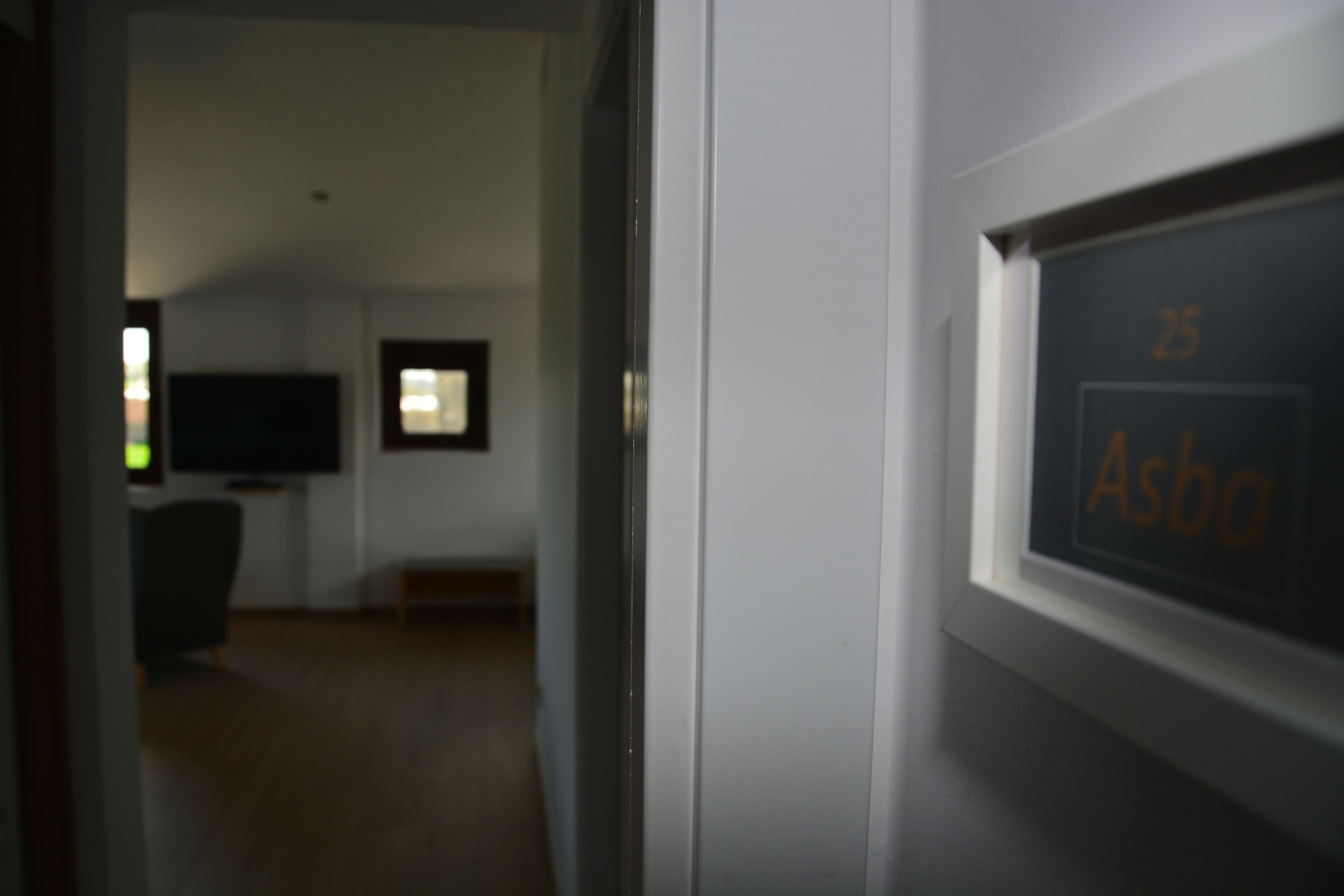 A room with a television, a window, and a door with a sign.