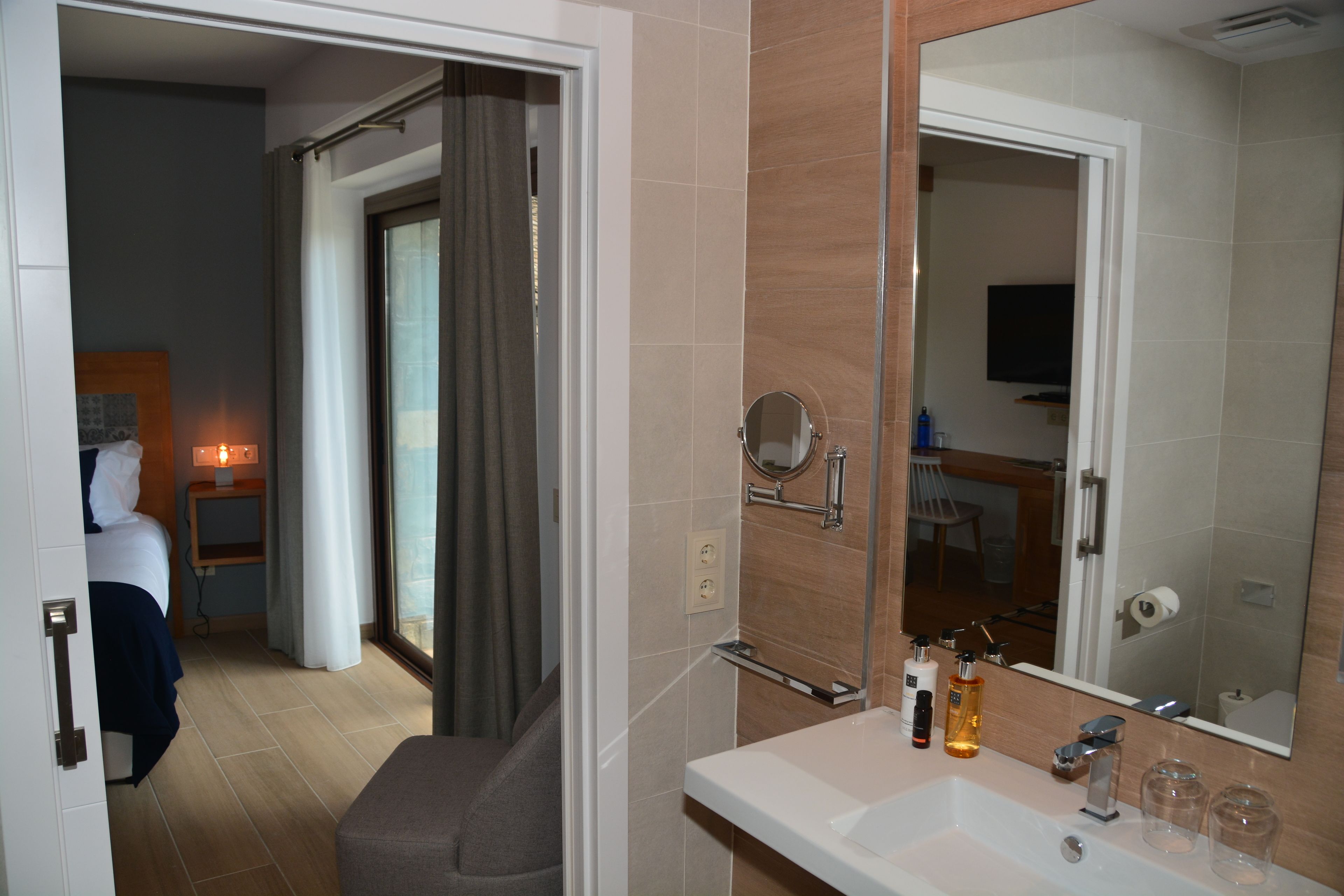 Un baño de hotel con un espejo grande, un lavamanos y artículos de aseo.