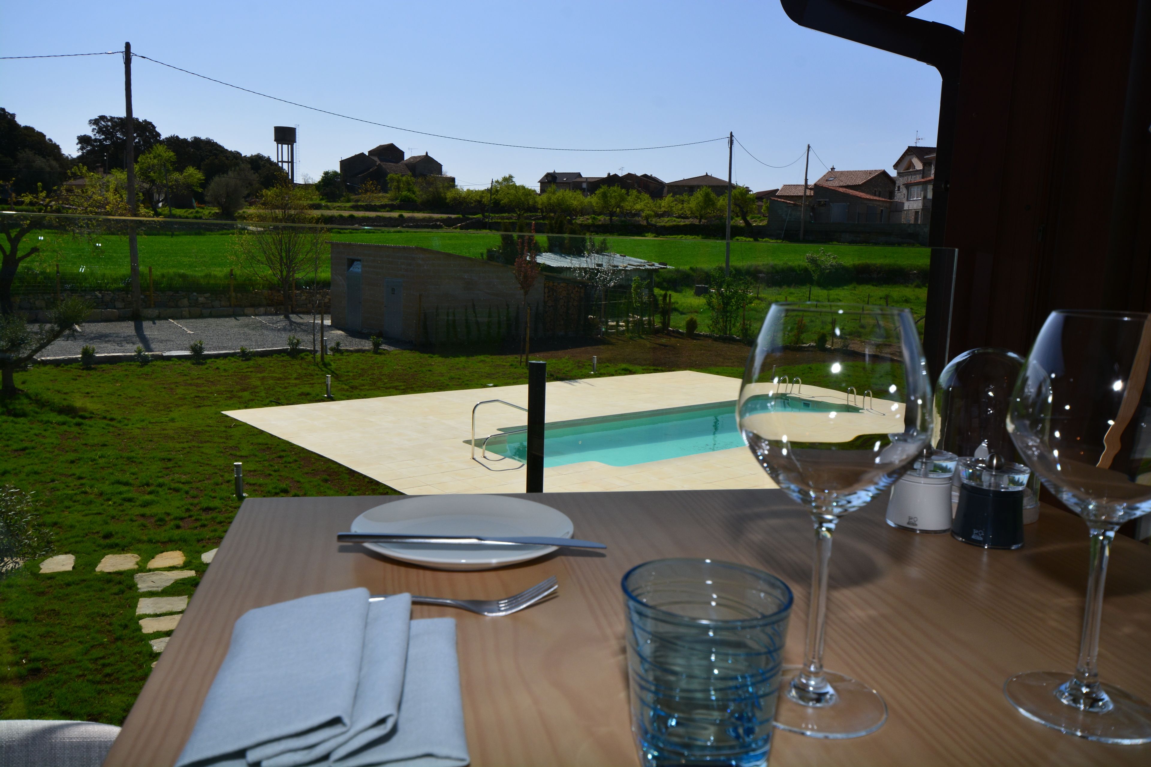 Un tavolo da pranzo con vista su una piscina e un'area verde.