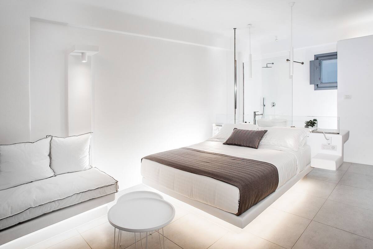 Un dormitorio moderno con cama, mesita de noche y una pequeña mesa redonda.