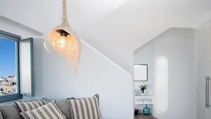 A modern living room with a curved sofa, a hanging light fixture, and a view of a cityscape through a large window.