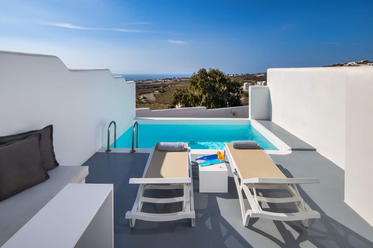 Zona de piscina en la azotea con dos sillones de relax y una pequeña mesa, con vistas a un paisaje pintoresco.