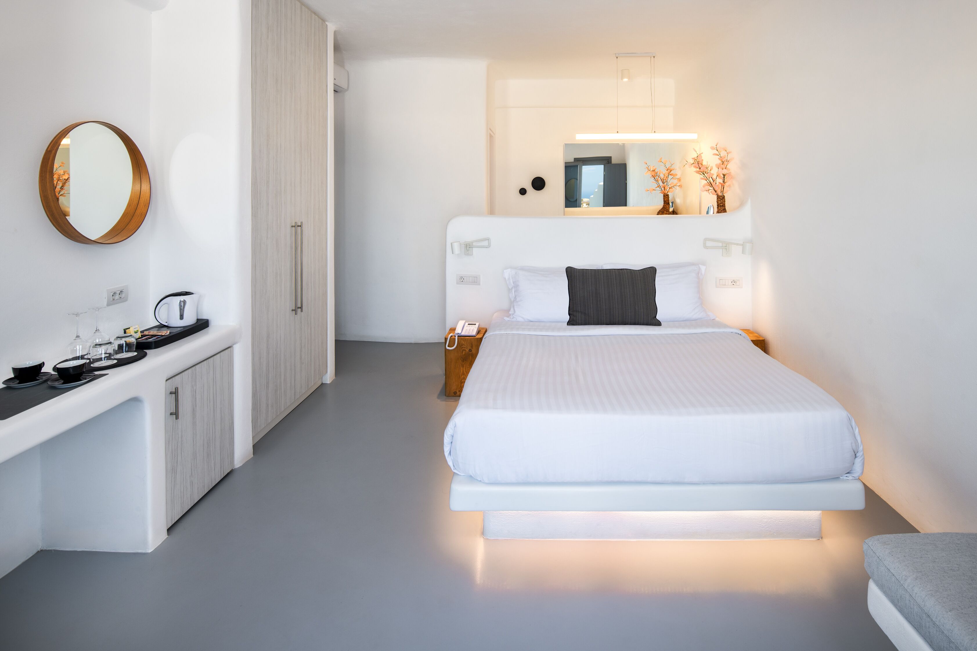 A modern bedroom with a bed, bedside table, and a mirror.