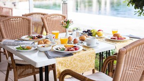 A breakfast table set with plates of food, drinks, and a newspaper. - Brijuni Hotel Neptun (Pula)