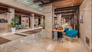 A modern lobby with a glass ceiling, a reception desk, seating areas, and a sign reading "Internet cafe". - Brijuni Hotel Neptun (Pula)