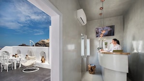 A reception area with a desk, chairs, and a hanging chair. - Athina Aperto Suites (Santorini)