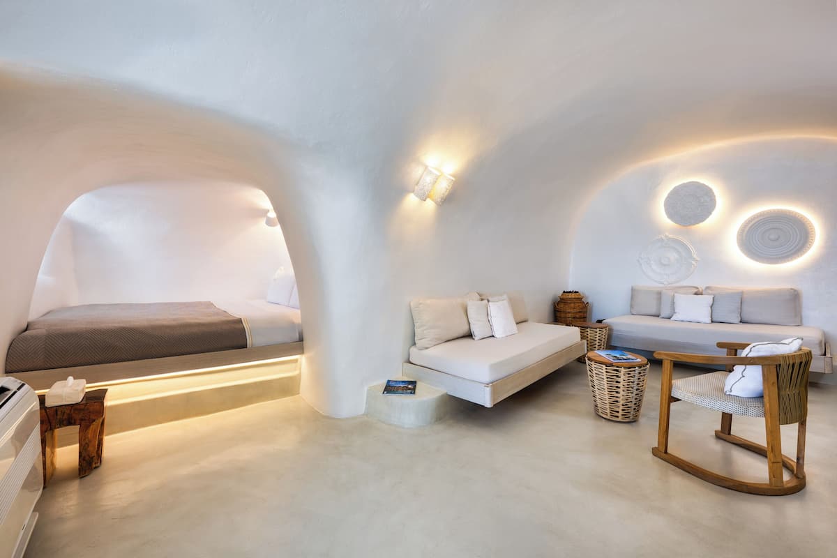 Quarto moderno e minimalista com cama, sofá e uma pequena mesa com cadeira.