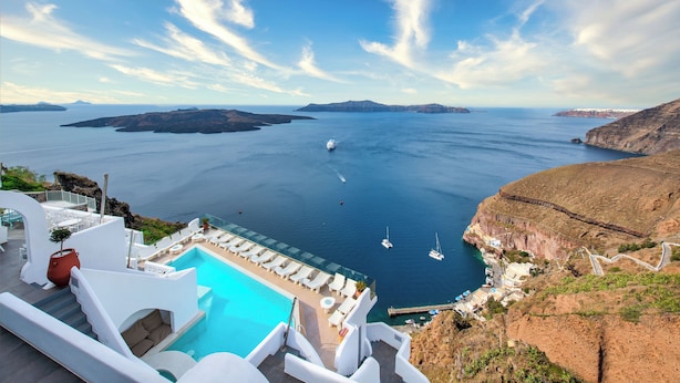 A resort with a pool, lounge chairs, and a view of the sea and islands. - Athina Aperto Suites (Santorini)