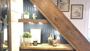 Een keuken met donkere kastjes, een houten trap en planken met planten en keukengerei.