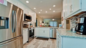 Una cocina moderna con electrodomésticos de acero inoxidable, armarios blancos y encimera de mármol.
