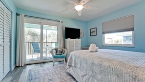 Un dormitorio con cama, televisión, ventilador de techo y vistas al exterior.