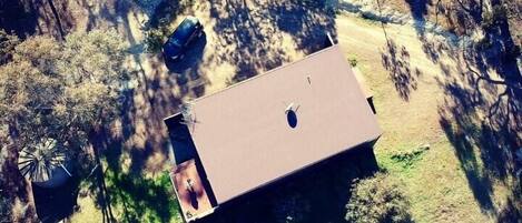 Une vue aérienne d’une maison avec un toit plat, une terrasse bien visible et un véhicule garé à proximité.