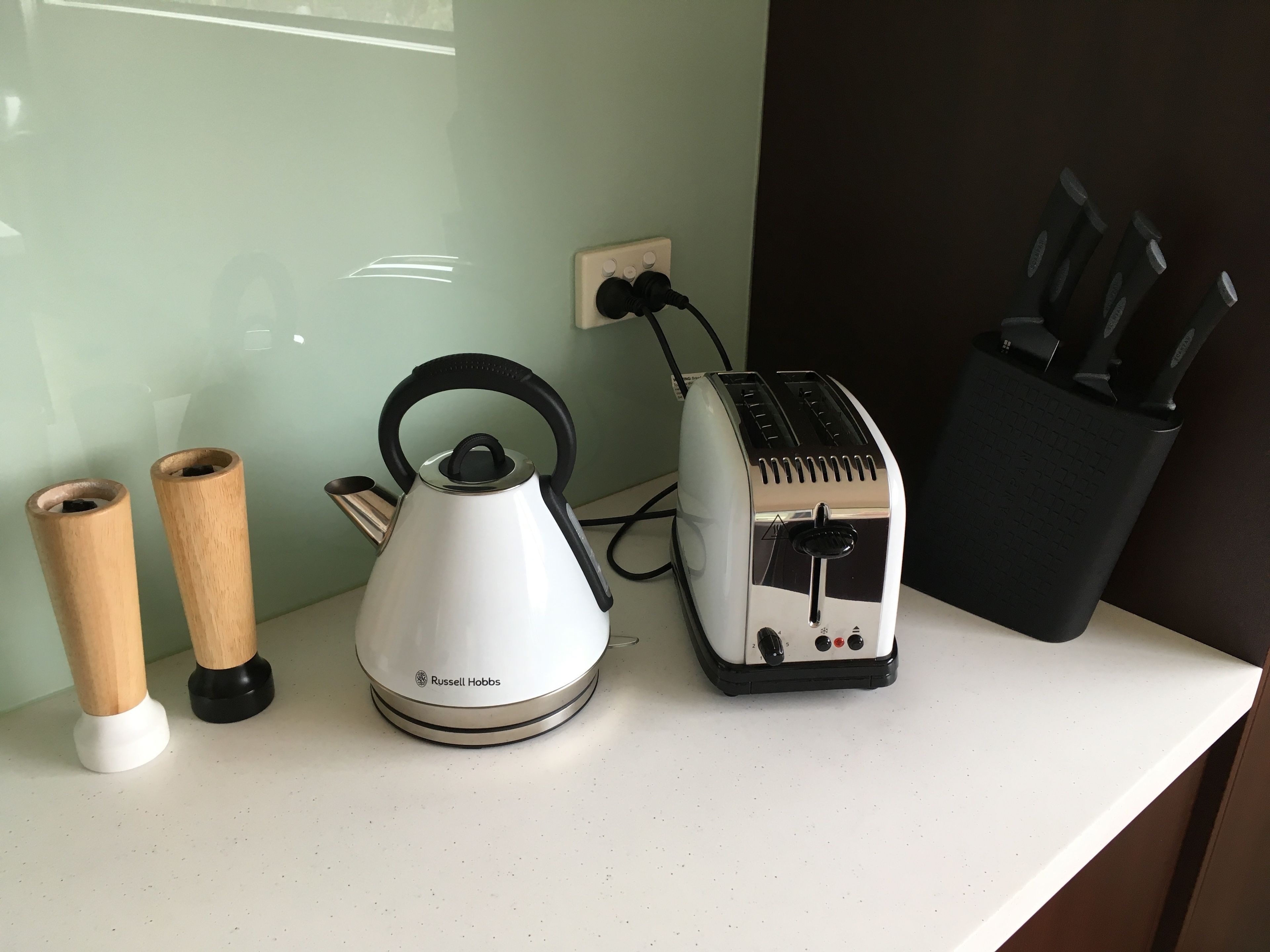 Un plan de travail de cuisine avec une bouilloire, un grille-pain et un porte-couteaux.
