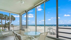 A beach view from a covered patio with a glass table and white chairs. - Island House Beach Resort 3S (Siesta Key)