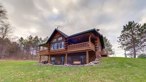 Eine Blockhütte mit Balkon, Veranda und Blick auf den umliegenden Wald.