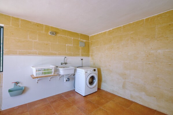 A small laundry room with a washing machine, a sink, and a laundry basket. - Modern Spacious Maisonette, Valley and Sea Views. A/C, Wi-fi. (Xaghra)
