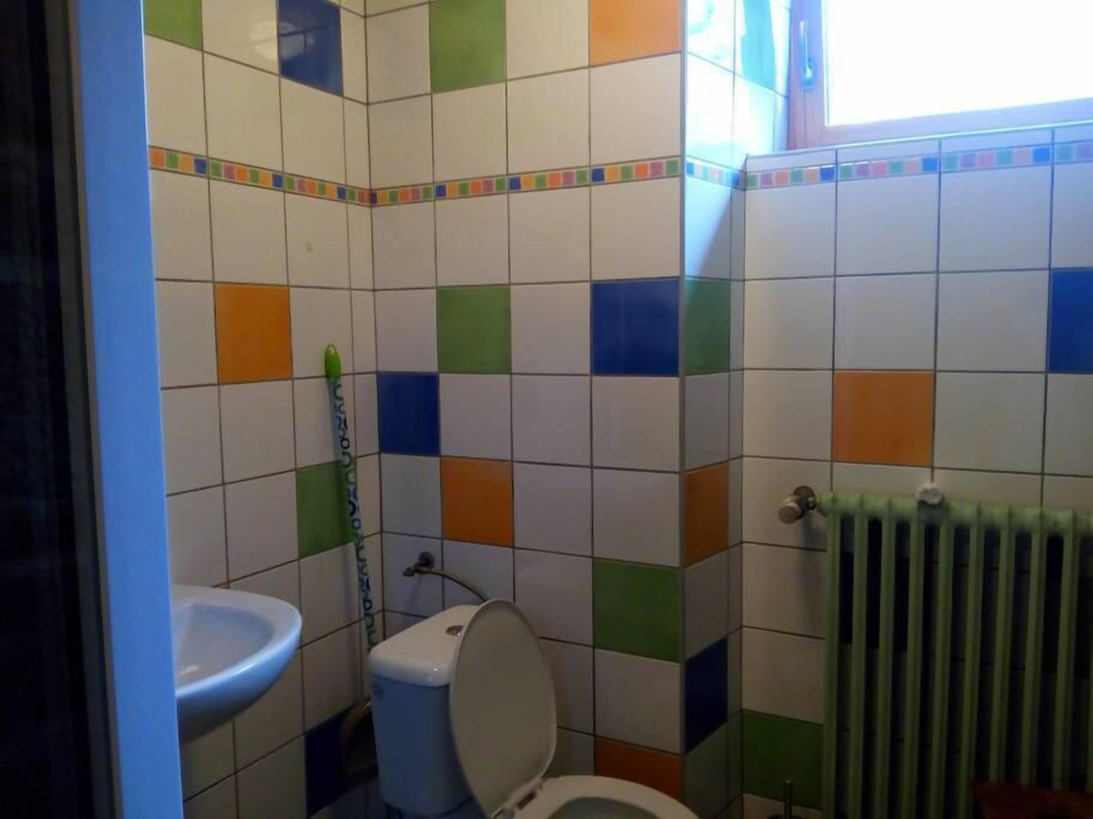 A bathroom with a toilet, sink, and radiator.