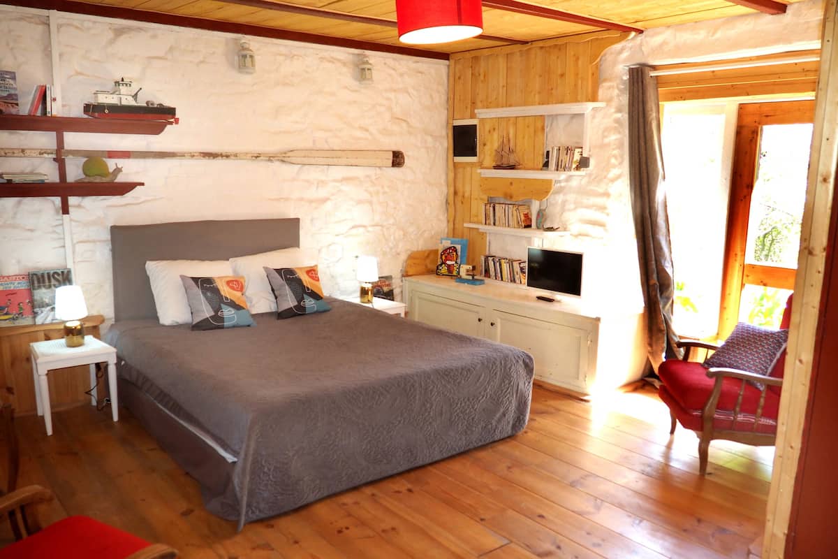 Un dormitorio acogedor con una cama grande, mesitas de noche, un televisor y una estantería.