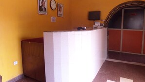 A reception area with a curved white reception desk, a clock, and two framed photographs on the wall.